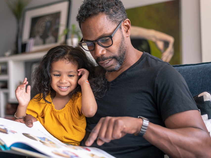 A father reads a picture book with his young daughter